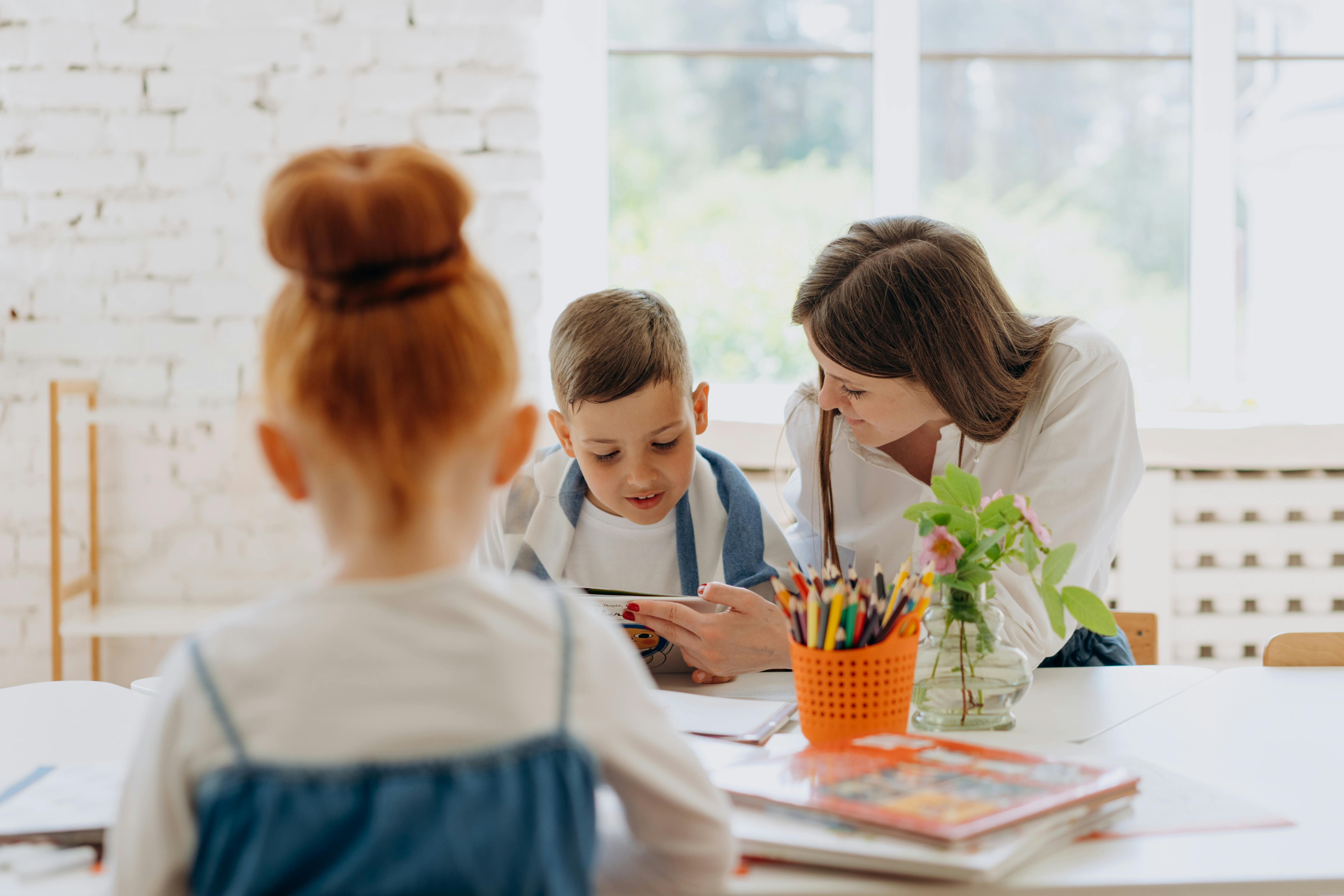 la maitresse en classe est auprès d'un enfant
